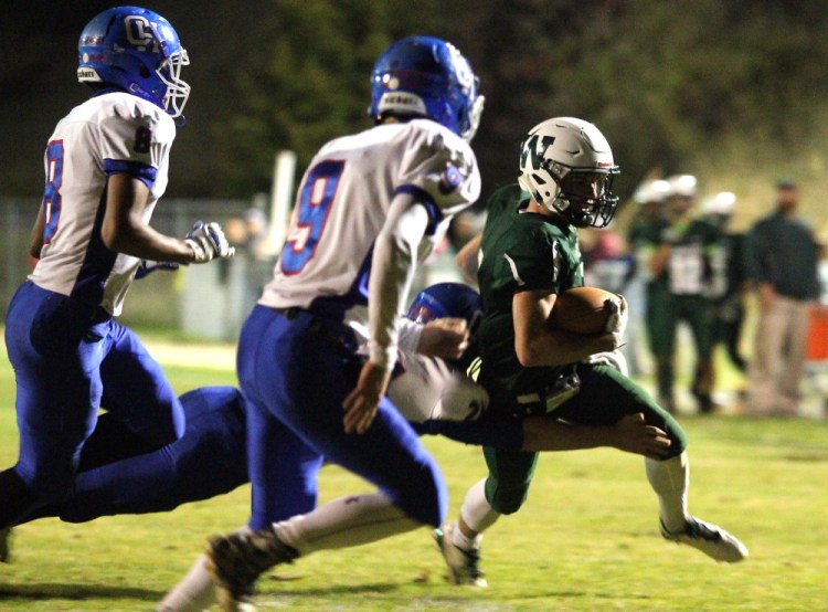 Winthrop/Monmouth's Nate Scott tries to find the end zone while being tackled by Oak Hill's High School's Brian Thorpe during first-half action on Friday night in Winthrop. Also in persuit of Scott are Oak Hill's Darryn Bailey (8) and Danny Buteau (9).