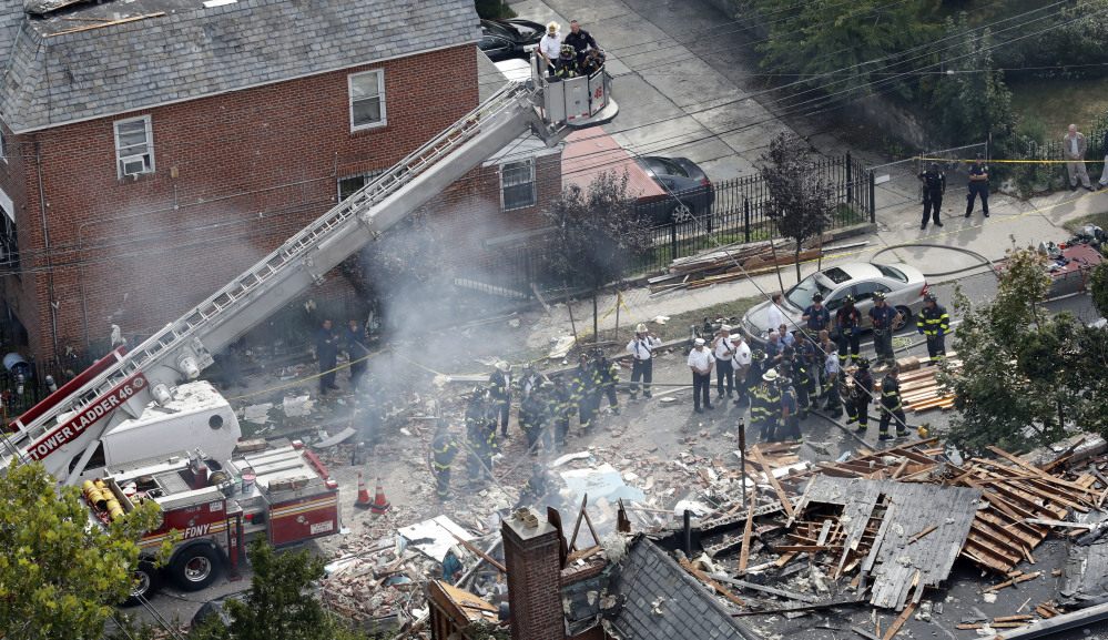 A house smolders Tuesday at the scene of a house explosion in the Bronx borough of New York. Two suspects were arrested on drug charges while officials try to determine if they should face more serious charges after a firefighter died.
