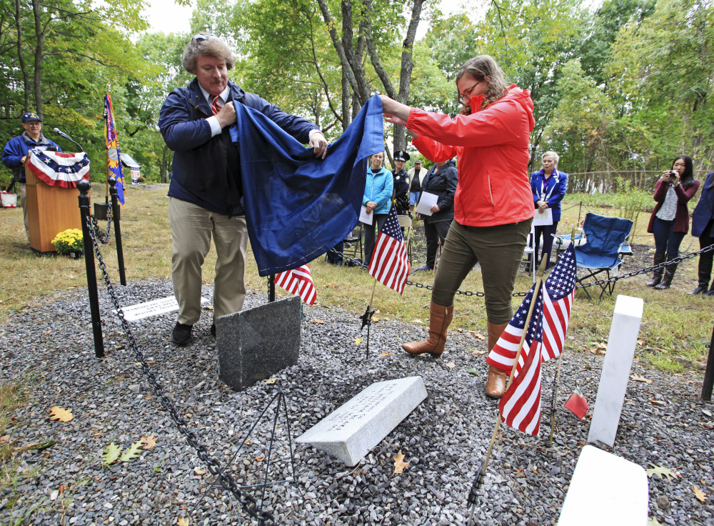 Herbert Adams and Samantha Allshouse unveil a grave marker in memory of William Blake at Grand Trunk Cemetery in Portland on Sunday. Blake was a private in the militia of a Massachusetts regiment called up to defend the port of Portland from the British in September 1814.