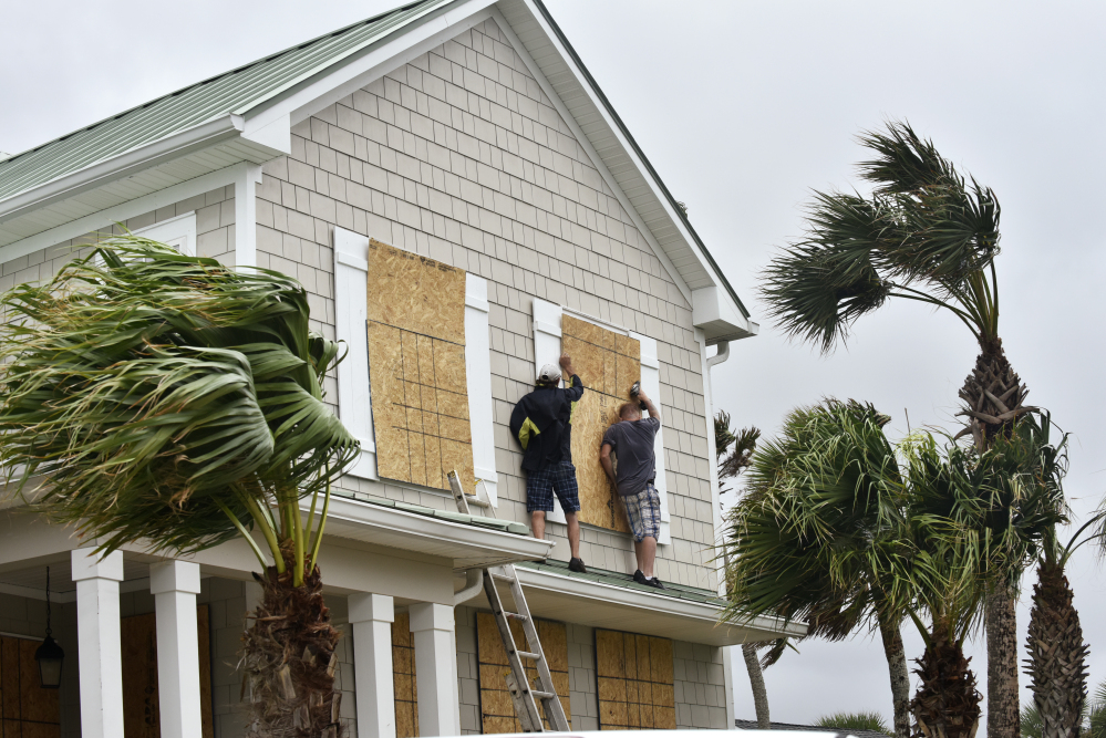 Workers in Ponte Vedra Beach, Fla., put plywood over windows of a home Wednesday in preparation for Hurricane Matthew. Officials ordered evacuations along the East Coast as the storm tore through the Bahamas and took aim at Florida, where the governor urged coastal residents to "leave now" if they were able.
