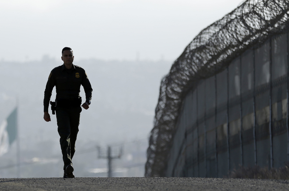 Border Patrol agent Eduardo Olmos walks near the fence separating Tijuana, Mexico, and San Diego last June.