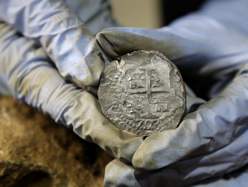 A lifesize replica of the Whydah Gally is desplayed, above, at the Whydah Pirate Museum in Yarmouth, Mass. At left, a silver coin recovered from the wreckage of the Whydah Gally.