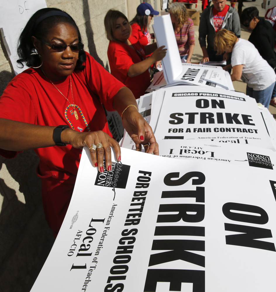 Retired Chicago school teacher Patricia Lofton counts through a stack of picket sign for Chicago Teachers Union members to pick up Monday in Chicago.