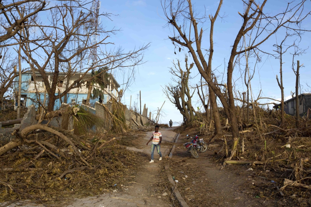 A man walks past the debris left by Hurricane Matthew in Haiti on Monday. Nearly a week after the storm hit, some communities have yet to receive any assistance. l