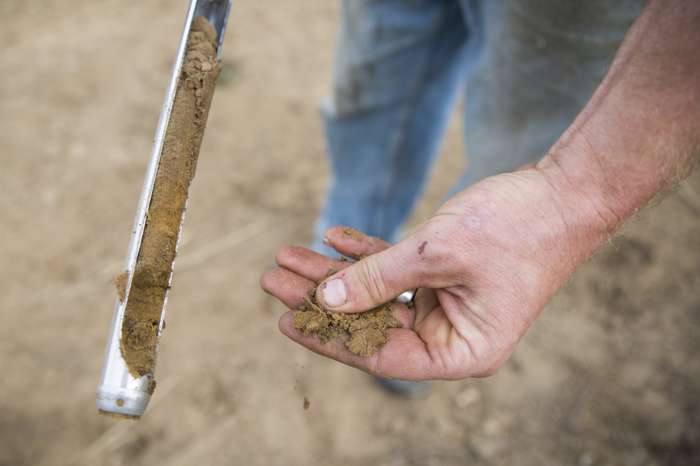 Steve Sinisi sifts dirt through his fingers after taking a soil sample at his 70-acre farm in Durham. "It's like powder. Dry as a bone," he said.