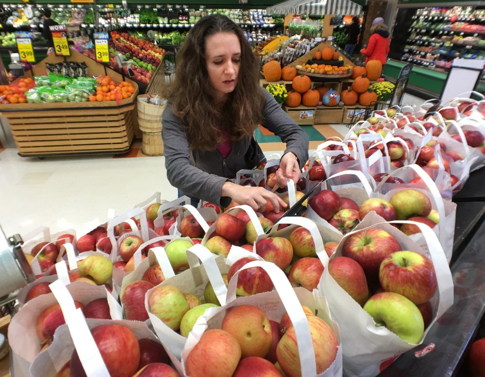 Kati Corlew picks out a bag of apples from Rowe Orchards while grocery shopping at Hannaford in Hampden on Oct. 15. Corlew concentrated on food choices and packaging in her quest to cut down on waste this semester.