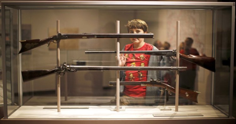 Bodhi Smith of Farmingdale, on a field trip to the Maine State Museum in Augusta, surveys a display of antique rifles produced by Maine gunsmiths in the 1800s.