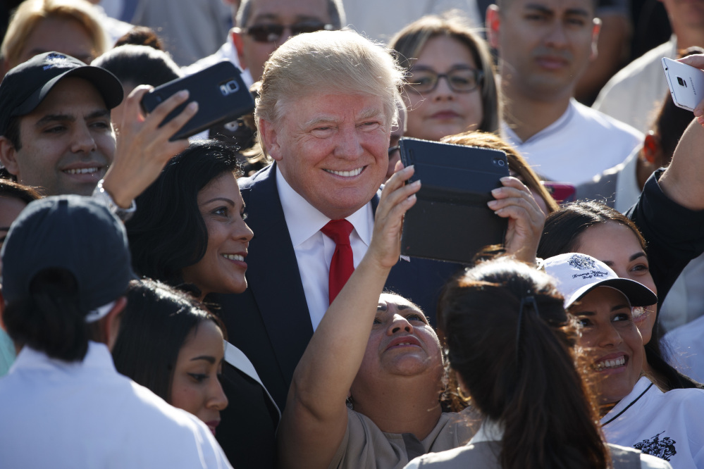 Republican presidential candidate Donald Trump poses for photographs during a campaign event with employees at Trump National Doral on Tuesday in Miami. Trump has railed against Obamacare in the abstract for months, often citing the risk of premium increases as a rationale for scrapping the program.