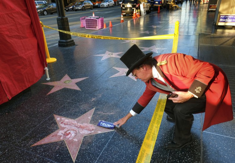 Gregg Donovan, who calls himself the unofficial ambassador of Hollywood, places a sticker for Republican presidential candidate Donald Trump on Trump's vandalized star on the Hollywood Walk of Fame on Wednesday in Los Angeles.