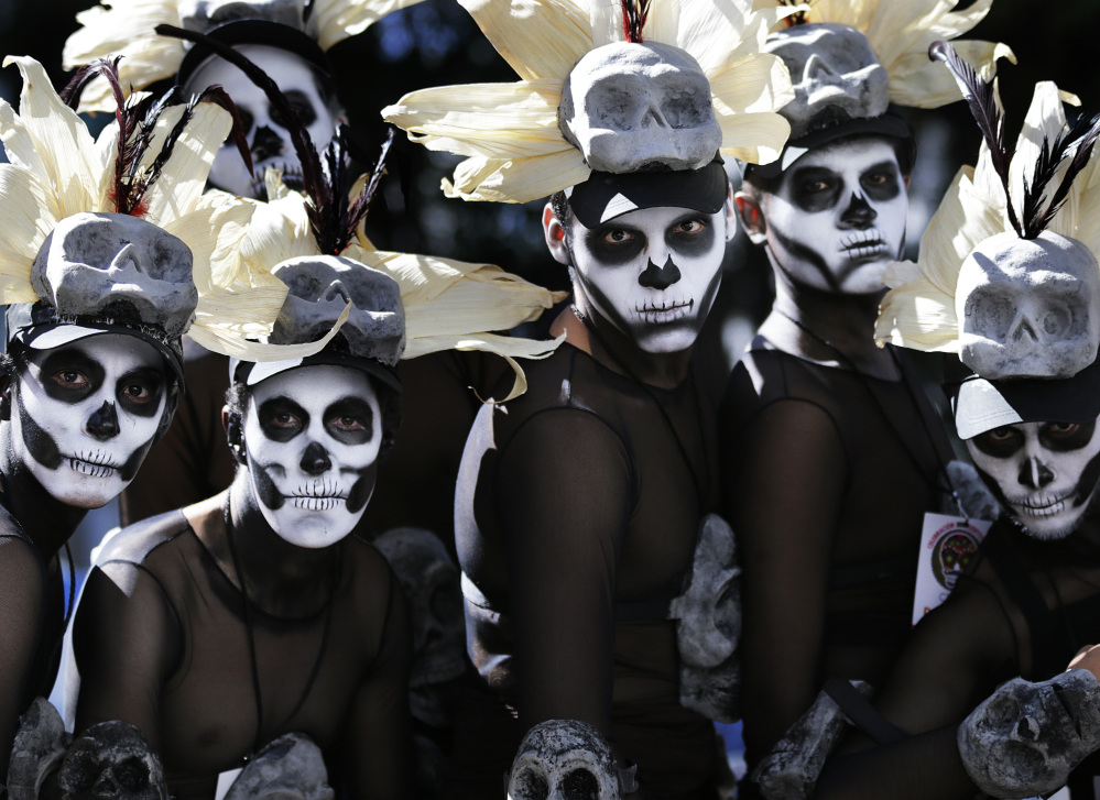 Men wait for a Day of the Dead parade to begin in Mexico City on Saturday. Traditional Day of the Dead celebrations are changing under the influence of Hollywood movies.