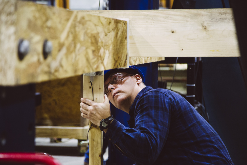 The University of Maine's Advanced Structures and Composites Center technician Walter Morris checks the warp on a piece of lumber from a Norway spruce in Orono in December.