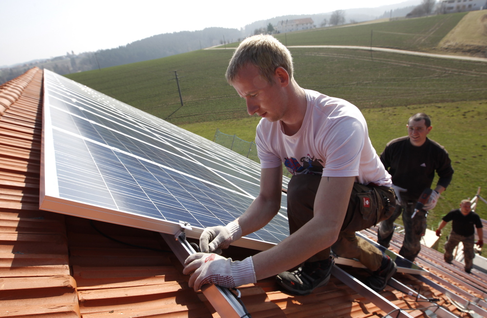 Workers install 320 square metres of solar panels on the roof of a farmstead barn in Binsham near Landshut March 21, 2012. German government plans cuts in the solar funding.     REUTERS/Michaela Rehle (GERMANY  - Tags: POLITICS BUSINESS ENERGY ENVIRONMENT) - RTR2ZNRR