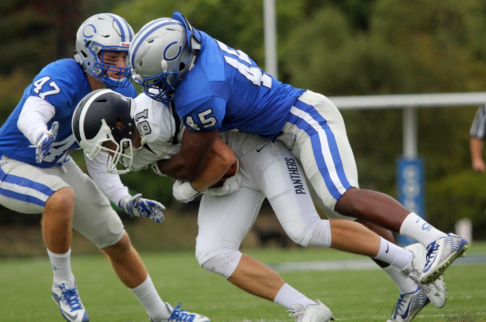 Colby College linebacker Sebastien Philemon tackles Middlebury College's James Burke with help from Bryan McAdams (47) during first-half action Saturday in Waterville.