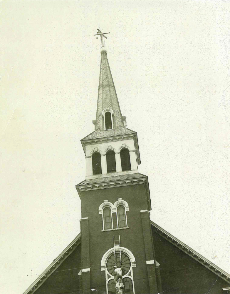 Joseph Armand "Blackie" Roy paints the cross atop the steeple of the former St. Francis de Sales Catholic Church on Elm Street in Waterville in this 1964 photo. The church was torn down in 2013 and replaced with senior housing.