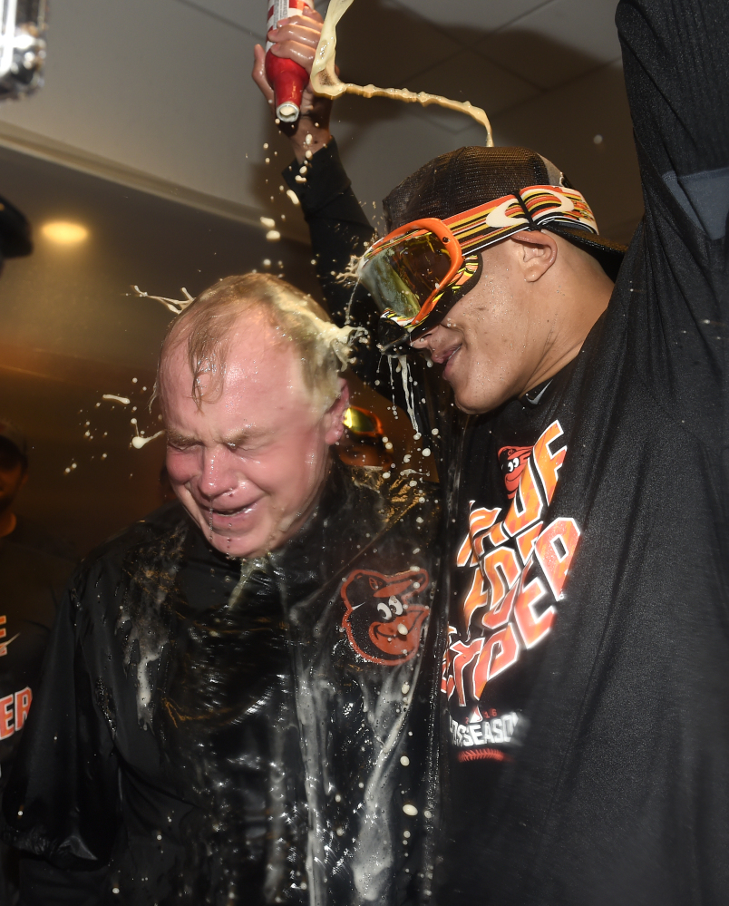 Baltimore Orioles manager Buck Showalter is doused with beer by Manny Machado in the visitors' clubhouse after the Orioles defeated the New York Yankees 5-2 to go to the playoffs Sunday in New York.