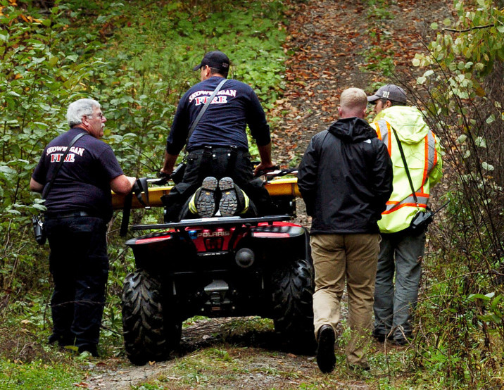 Skowhegan firefighters transport a gurney to the scene where the body of a male camp owner was found after his all terrain vehicle he was riding on went off a trail along the Whittemore Hill Road in Skowhegan on Sunday. Relatives reported him missing and Warden Sgt. Chris Simmons believes the fatality occurred several days before he was located.