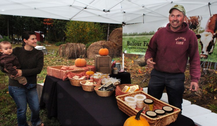 Doug Donahue of the Balfour farm in Pittsfield waits on farm visitor Jacklynn Taylor and her son Alder who were buying organic cheeses during Open Creamery Day on Sunday.