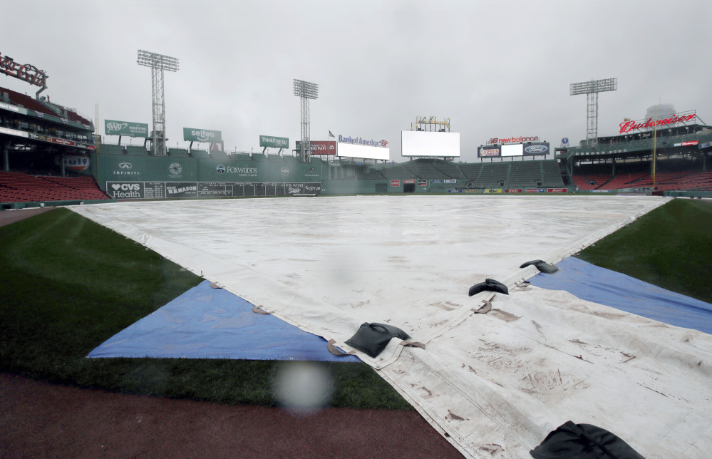 A tarp covers the infield at Fenway Park during steady rain before Game 3 of baseball's American League Division Series between the Cleveland Indians and the Boston Red Sox Sunday in Boston. The game was postponed until Monday.