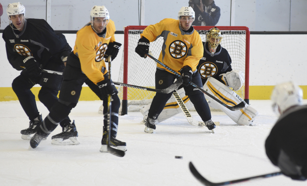 Bruins defenseman Zdeno Chara, left, starts to drop his stick on a shot to goalie Tuukka Rask, right, during practice in Boston on Tuesday. From left are Chara, center Patrice Bergeron, left wing Brad Marchand and Rask.