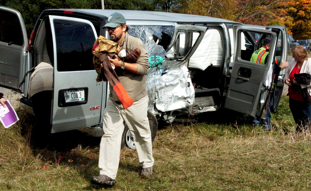 College of the Atlantic professor Todd Little-Siebold removes items from the wreckage of a school van that had nine students and staff inside when it collided with another van after turning on to the Crosby Brook Road in Thorndike to attend an event at the Maine Organic Farmers and Gardeners Association on Sunday. Little-Siebold said the students in the school van were shaken up and received relatively minor injuries.