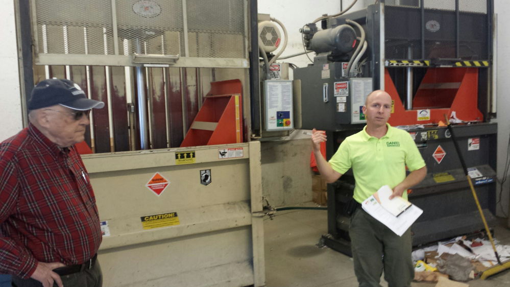 Richard Pierce, left, who worked for the Oakland Transfer Station for 22 years before recently retiring, listens as station manager Daniel Hapgood explains the recycling process to the committee while standing in front of the machines that compress the paper and cardboard.