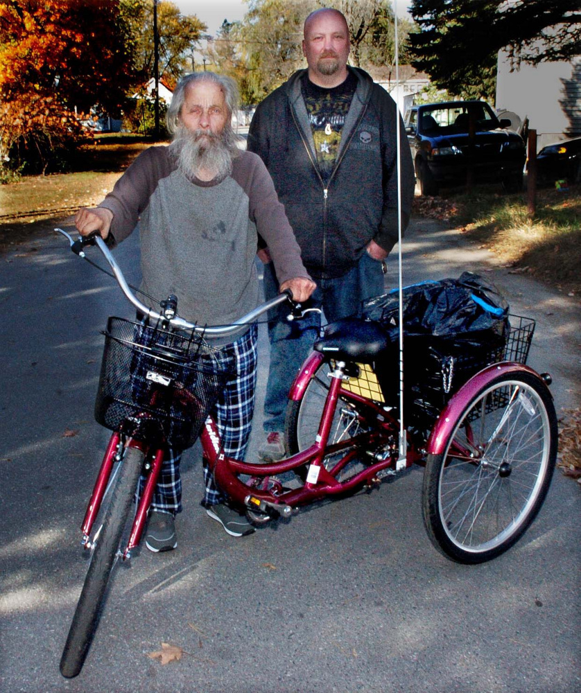 Neil Woodard, left, known as the "Bottle Man," stands beside his new tricycle he named Luka on Monday after his other tricycle was damaged and Woodard was injured in a fall. Next to Woodard is Rick Sisco, who spearheaded the effort to raise money for the new tricycle.