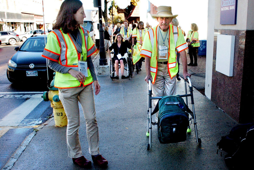 Peter Garrett uses a walker as others in wheelchairs navigate sidewalks Wednesday in Waterville to illustrate challenges in mobility for people with disabilities during a GrowSmart Maine seminar in Waterville. At left is Jill Johanning, who watched during the demonstration.