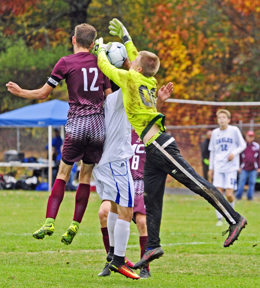 MCI's Carter Richmond and Erskine's Sage Hapgood Belanger, center, and keeper David McGraw jump for a ball in front of the net during a Class B North preliminary game Saturday in South China.