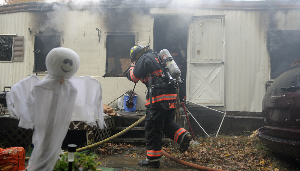 A firefighter enters a home on Leighton Lane in South Gardiner that was destroyed by fire on Tuesday.