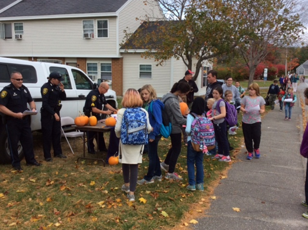 Sgts. Scott Taylor, Laura Drouin and Christian Behr collect Operation Pumpkin contest drawings from school-age children on Glenridge Drive in Augusta. In return each child received a pumpkin.