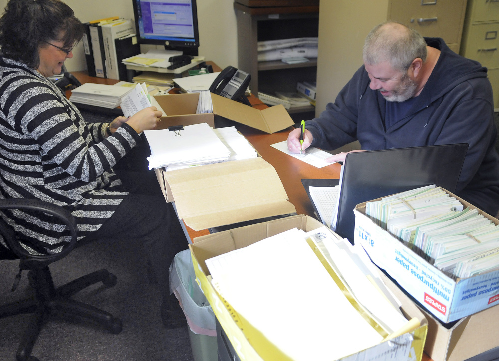 Mark Luken signs a ballot Tuesday before handing it over to West Gardiner Town Clerk Angela Phillis. Phillis said hundreds of ballots have been cast early at the West Gardiner Town Hall.