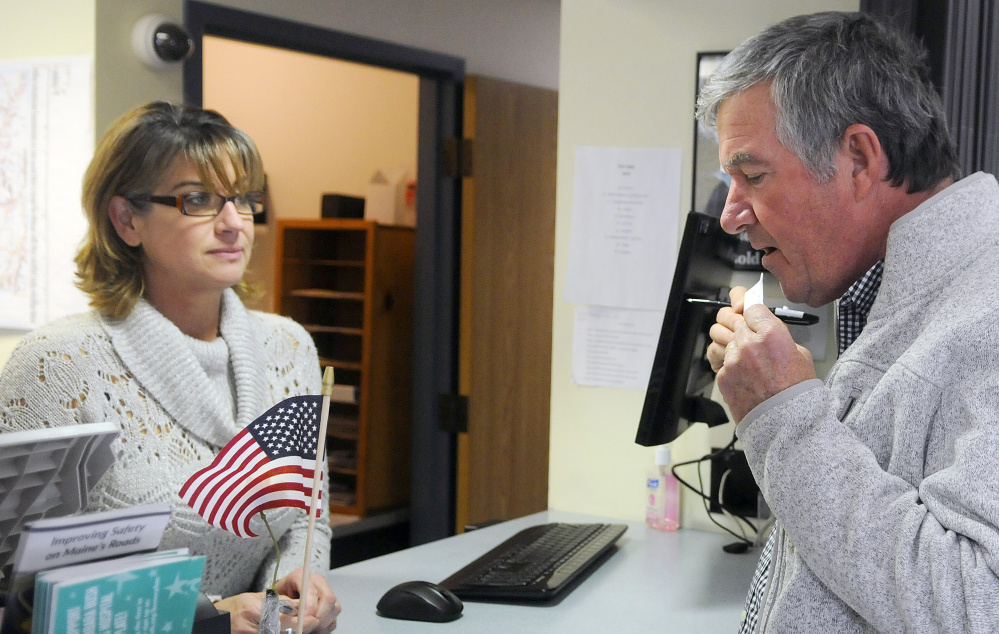 Steve Kalenda seals a ballot Tuesday before handing it over to Monmouth Deputy Town Clerk Kim Dalton. Towns are reporting a higher-than-normal early voting trend.
