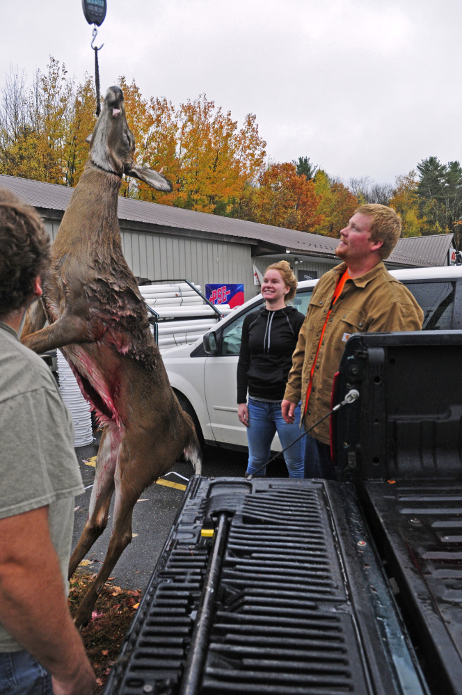 Roxanne Carter, left, and Matthew Carter look up at the scale Saturday to see how much the deer Matthew Cater shot earlier in the day weighs after tagging it at Audette's Hardware in Winthrop.