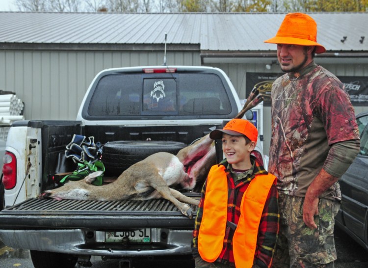 Blake Gemelli and his father, Eric Gemelli, talk about the deer that Blake got Saturday, the opening day of firearms season, at Audette's Hardware in Winthrop. The two had been out hunting Oct. 22 on youth day, but Blake didn't get one then.