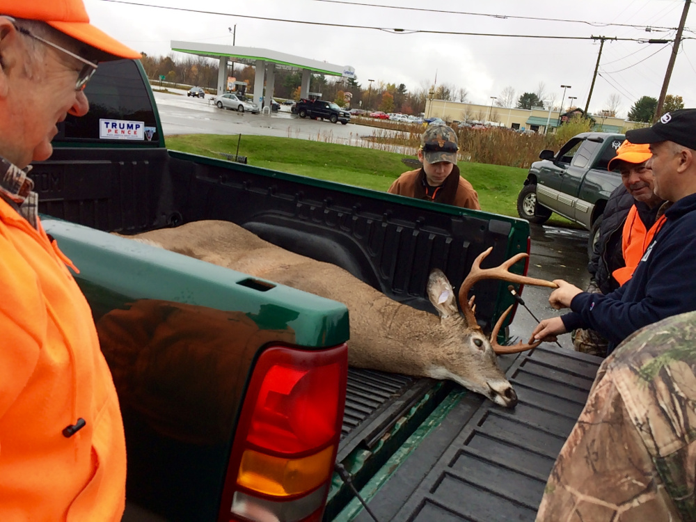 Ken Smith, 74, of Winthrop, left, smiles as a small crowd admires the 199-pound, nine-point buck he shot about 2 miles from his house Saturday morning. Saturday was the first day of the regular hunting season for Maine residents.