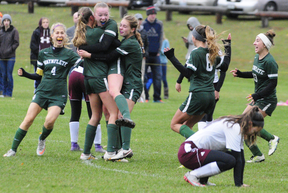 Waynflete teammates mob Lydia Giguere, jumping center, after she scored a goal in overtime to beat Monmouth Academy 2-1 in a Class C South semifinal Saturday in Monmouth.