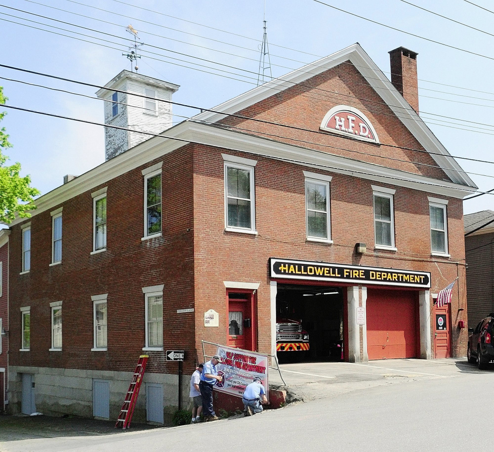 This May 2011 file photo shows Hallowell volunteer firefighters hanging a banner outside the fire station.