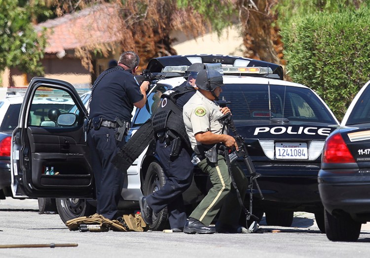 Officers watch a home in Palm Springs, Calif. where two police officers were killed and one wounded.