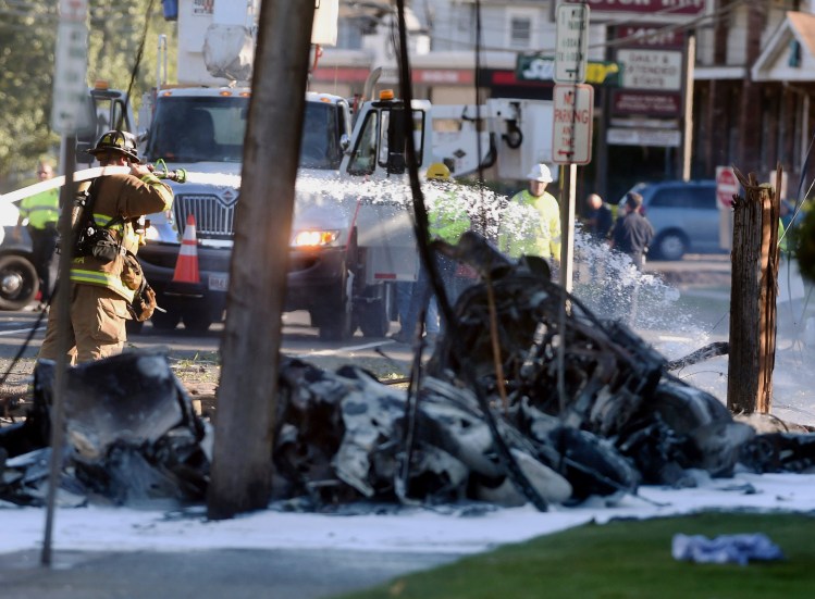 Firefighters extinguish the fire after a plane crashed on Main Street in East Hartford, Conn., on Tuesday.