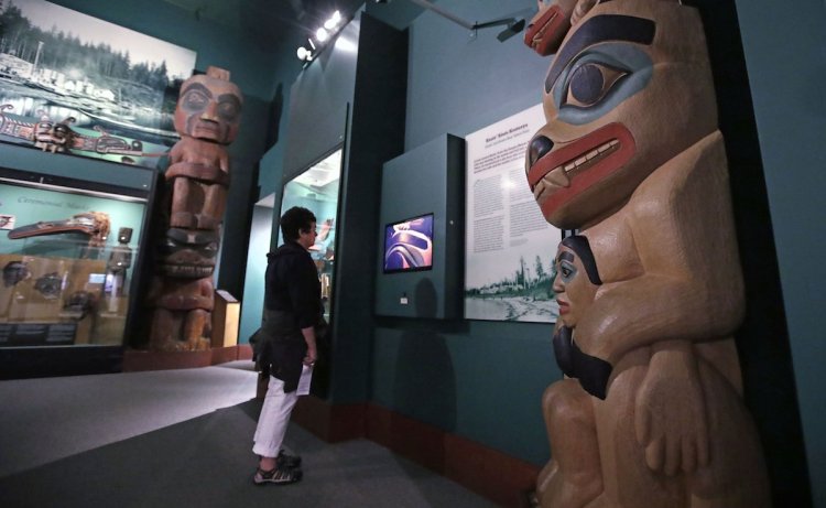 A visitor stands among totem poles as she watches a video as part of Hall of the North American Indian exhibit, at the Peabody Museum of Archaeology & Ethnology at Harvard University in Cambridge, Mass., Thursday, Oct. 13, 2016. The Peabody, one of the oldest and largest museums in the world focused on the study of societies and cultures, turns 150 years old this month.