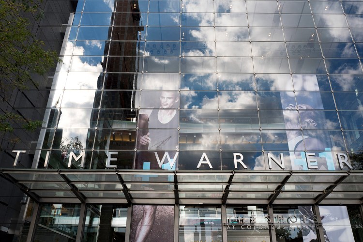 Clouds are reflected in the glass facade of the Time Warner building in New York. AT&T plans to buy Time Warner for $85.4 billion.