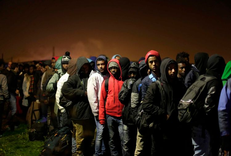 Migrants line up to register at a processing center in the makeshift migrant camp known as "The Jungle" near Calais, northern France, Monday. French authorities say the closure of the slum-like camp will last approximatively a week in what they describe as a "humanitarian" operation. <em> Associated Press/Emilio Morenatti</em>