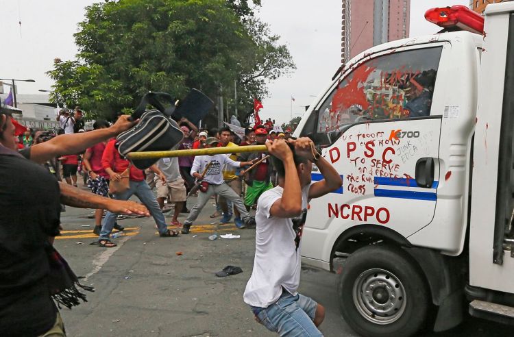 Protesters hit a Philippine National Police van after it rammed into the crowd outside the U.S. Embassy in Manila, injuring an undetermined number of people Wednesday. <em>Associated Press/Bullit Marquez</em>