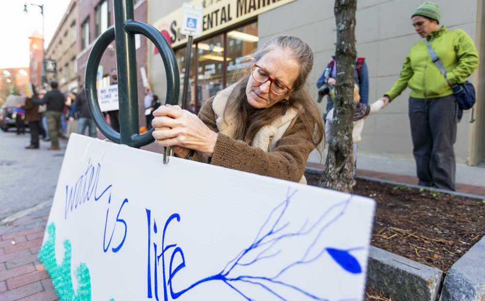 Gina Colombato hangs a sign outside Hillary Clinton's offices in Portland during a protest against the Dakota Access Pipeline.