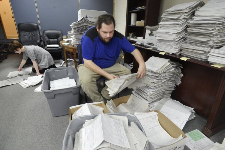 Staff and volunteers  for the marijuana legalization campaign are sorting petitions at their office in Falmouth. Office manager Shaun Bowen and volunteer Allison Cormier organize stacks of petitions at their headquarters. 