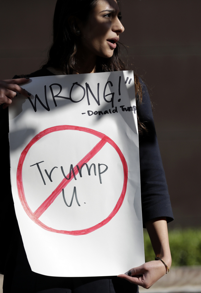 Senya Merchant holds a sign against Donald Trump's now-defunct Trump University on Friday in San Diego. Trump agreed to pay $25 million to settle several fraud lawsuits.