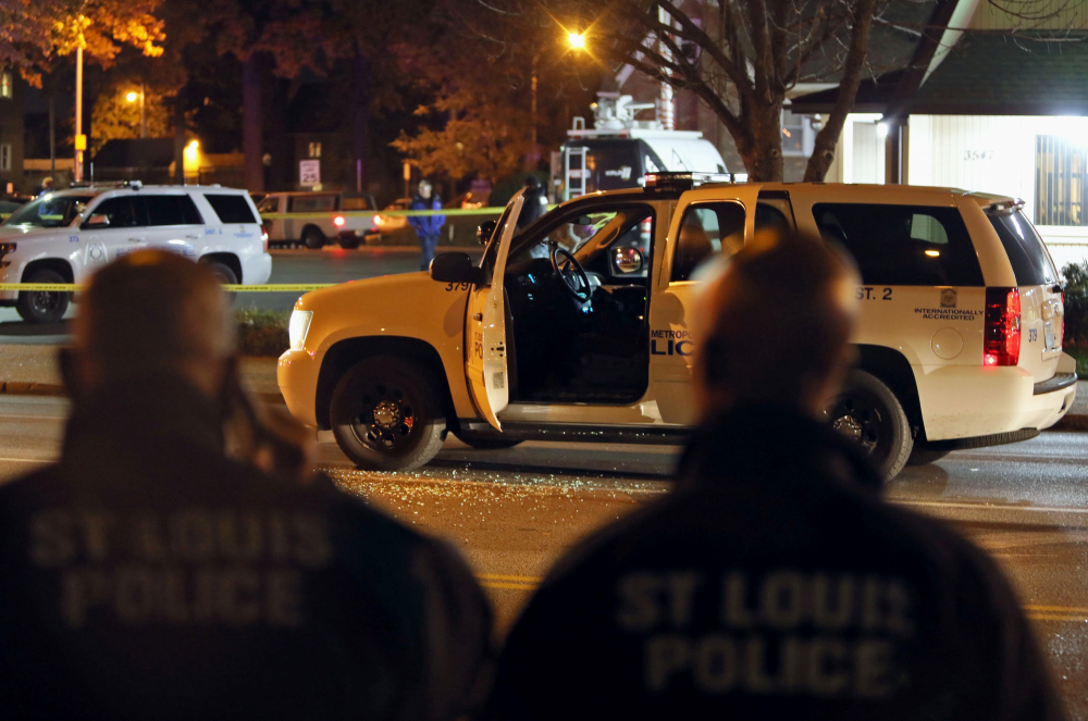 Police officers inspect a truck undercover police officers were riding in when it was shot through the windshield by a suspect they were following in St. Louis on Monday. The police and man engaged in a shootout that ended with the suspect being fatally shot.