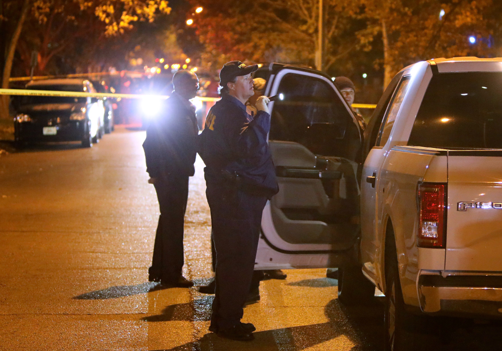 Police officers inspect a truck undercover police officers were riding when it was shot through the windshield by a suspect they were following in the 6500 block of Smiley Avenue Monday, Nov. 21, 2016, in St. Louis. The police and man engaged in a shootout in the neighborhood that ended with the suspect being fatally shot. The man who police shot is suspected of shooting a police officer earlier in the night and several other crimes in both St. Louis County and St. Louis city. (David Carson//St. Louis Post-Dispatch via AP)