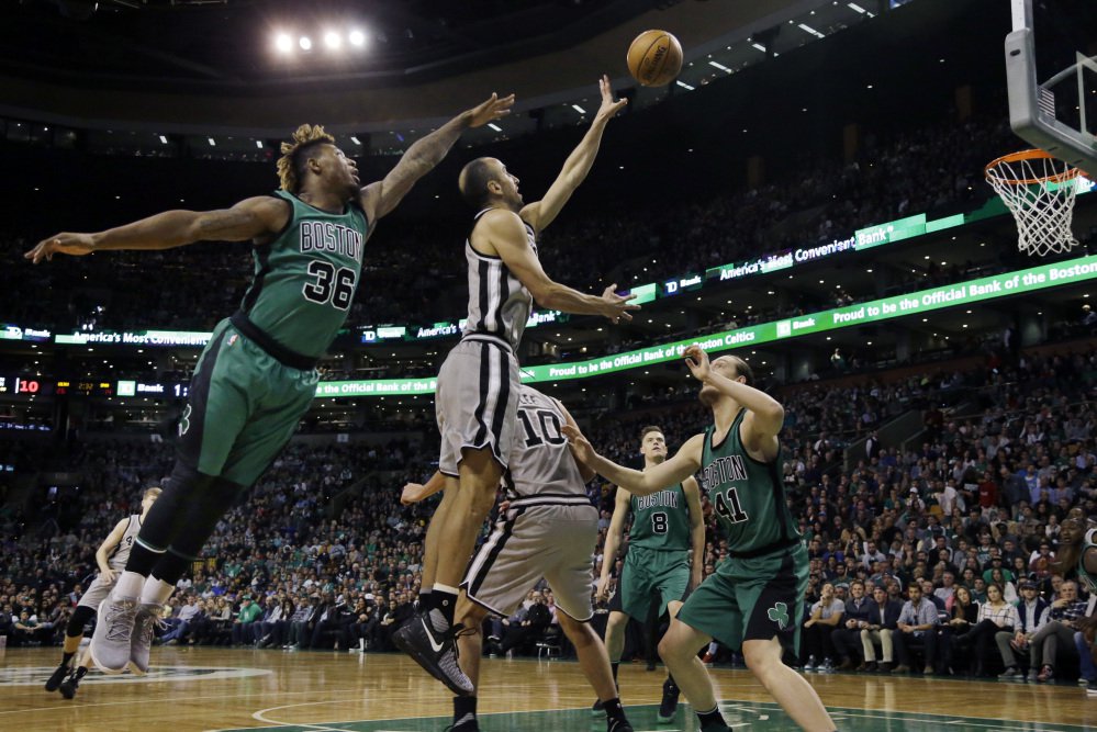 Spurs guard Manu Ginobili gets a shot off between Celtics guard Marcus Smart, left, and center Kelly Olynyk in the first half of the Spurs' 109-103 win Friday in Boston.