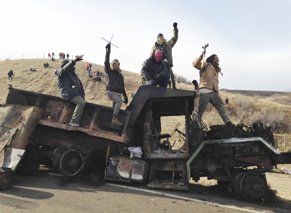 Protesters against the Dakota Access oil pipeline stand on a burned-out truck near Cannon Ball, N.D., on Nov. 21. Hundreds have been arrested at the protest site.